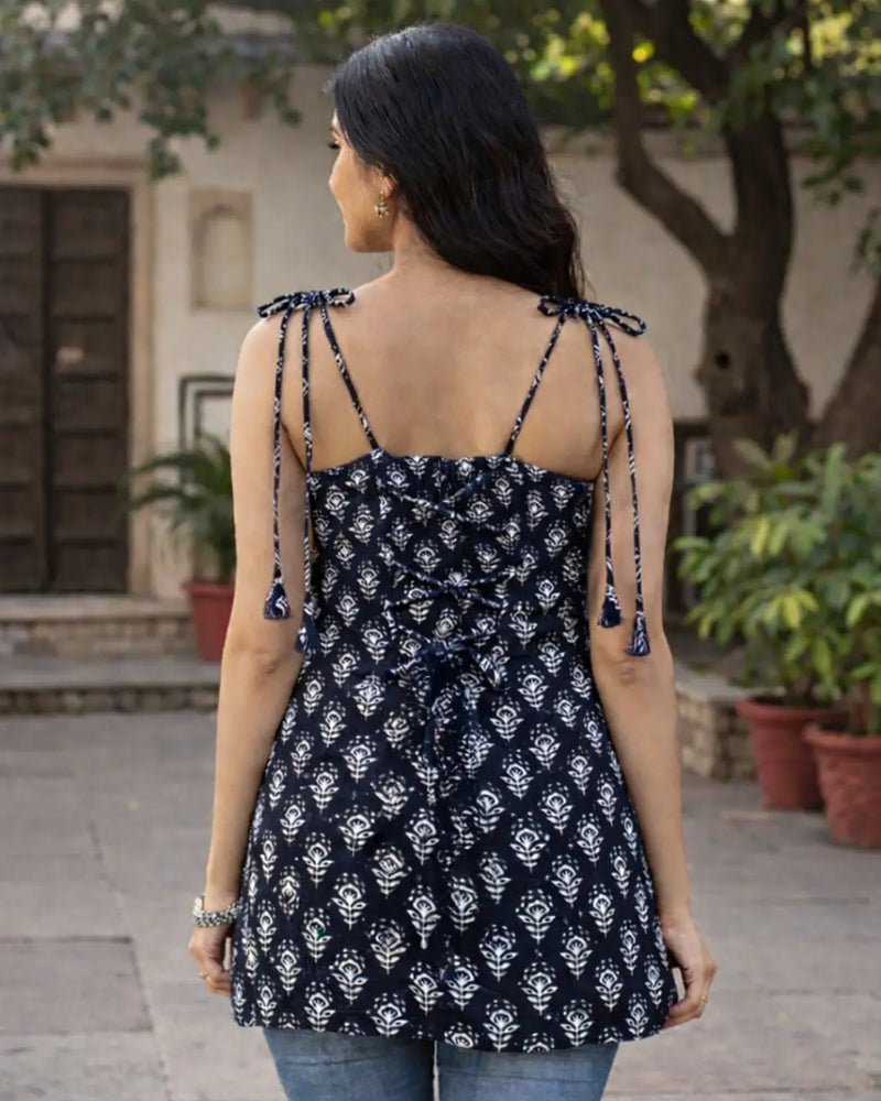 Woman wearing a black and white patterned top with tied straps in an outdoor setting.