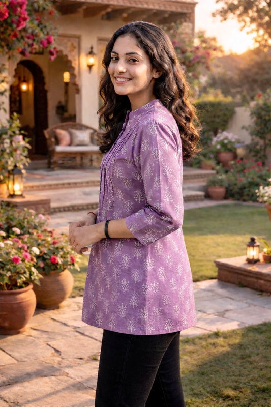 Woman wearing a purple floral top in an outdoor garden setting