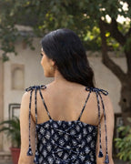 Woman wearing a black and white patterned dress with tie straps outdoors.