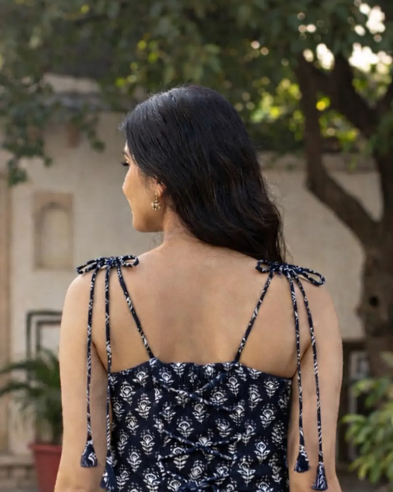 Woman wearing a black and white patterned dress with tie straps outdoors.