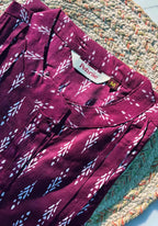 Maroon patterned shirt with a brand label on a textured surface